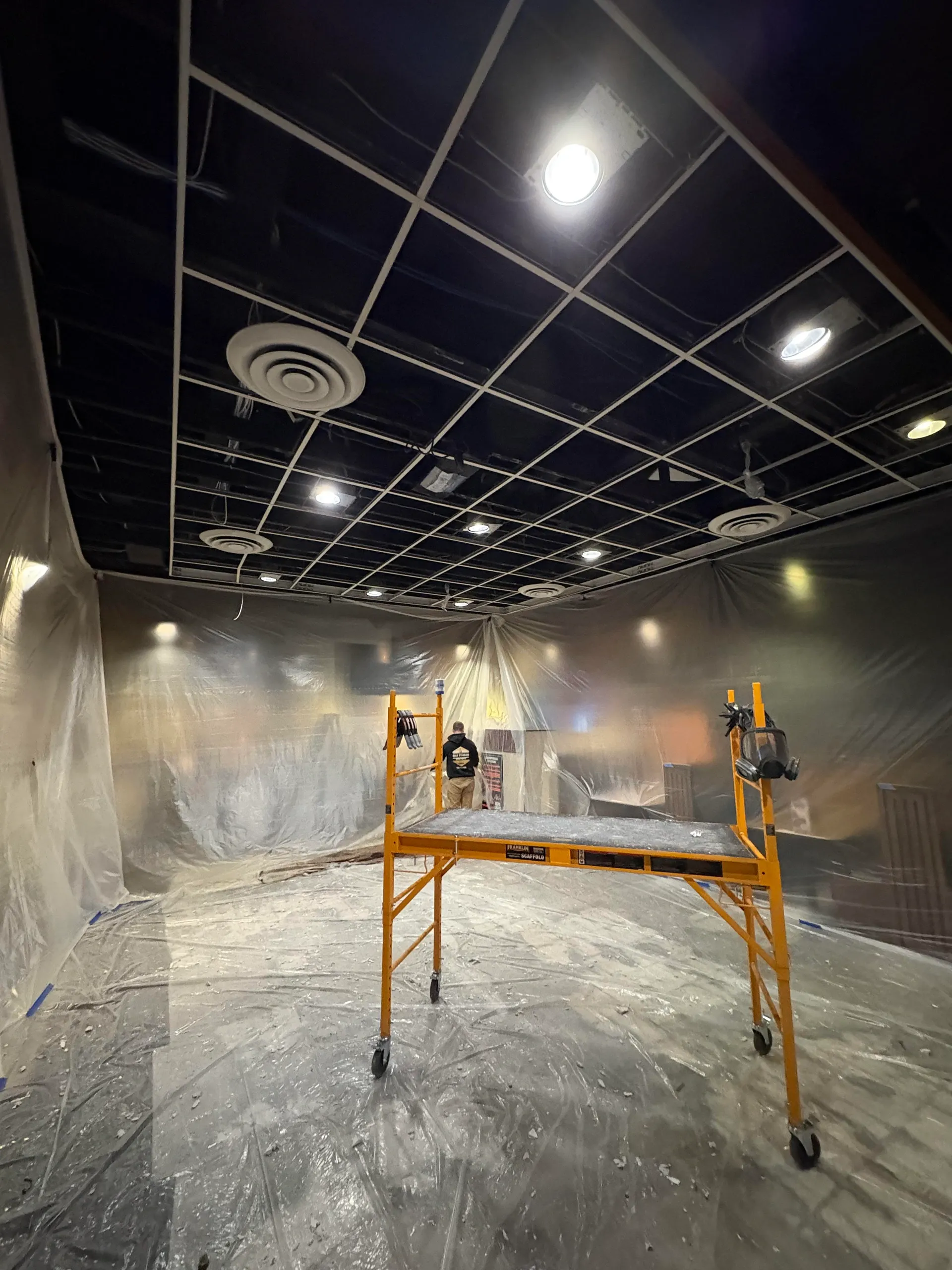 Commercial interior repaint in progress with masking and plastic sheeting